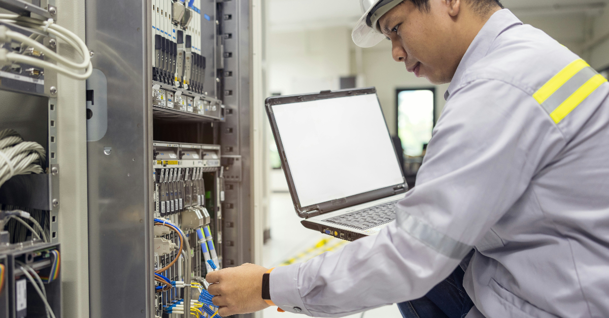 person connecting a wire to a network holding a laptop