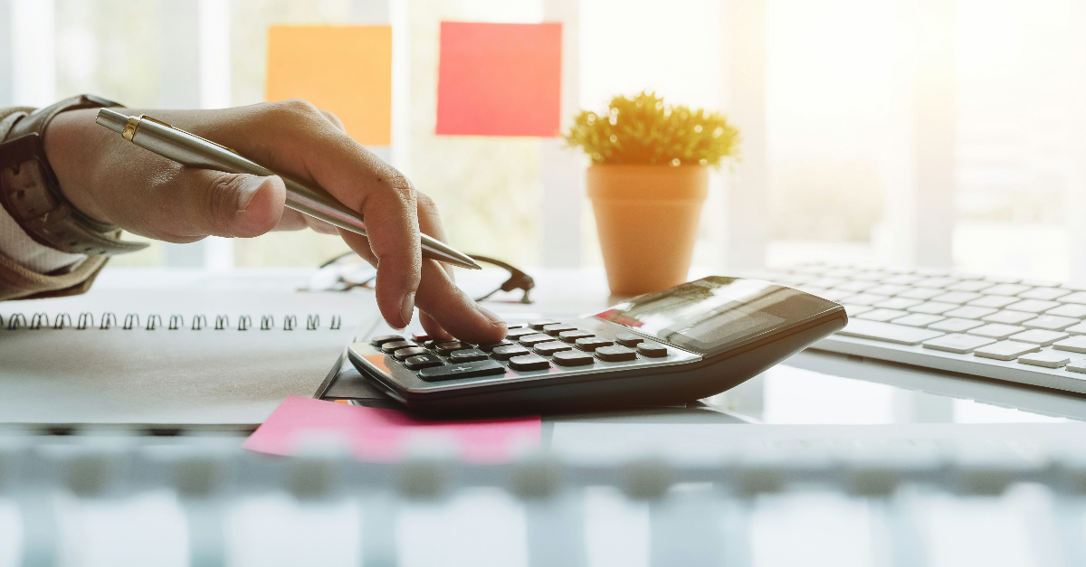 person holding pen using calculator